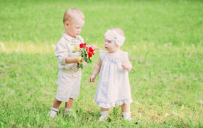 A little boy gives a bouquet of wild flowers to a girl
