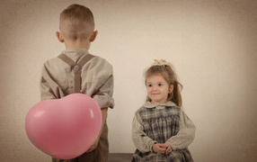 Маленький мальчик дарит девочке шарик в форме сердца