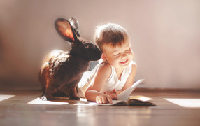 A little boy with a big black rabbit reading a book