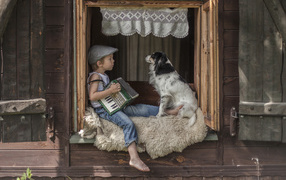 Маленький мальчик с гармошкой сидит на подоконнике с собакой