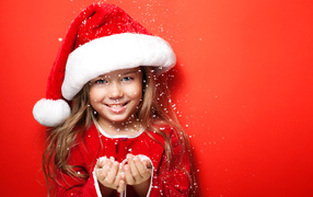 Маленькая девочка в новогодней шапке ловит руками снежинки