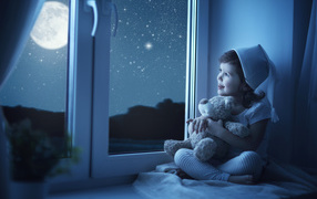 Маленькая девочка сидит на подоконнике с игрушкой ночью