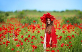 A little girl with a big beautiful wreath of red poppies on her head