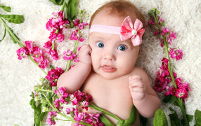 A little girl with a bow on her head is laying flowers