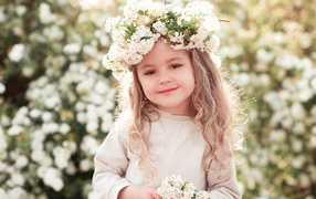 A little girl with a wreath of white flowers on her head