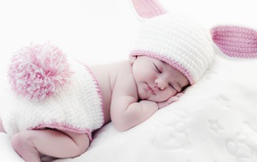 A little sleeping child in a knitted bunny costume