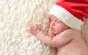 Маленький спящий ребенок в красном новогоднем колпаке