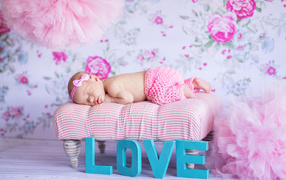 Спящий грудной ребенок в розовом костюме и надписью love
