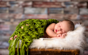 A sleeping baby under a green knitted plaid