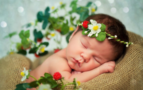 Спящий грудной ребенок с красивой повязкой на голове