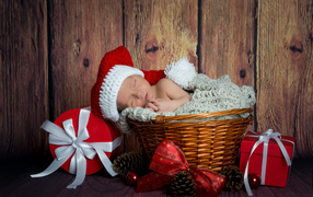 A small baby is sleeping in a wicker basket with Christmas gifts