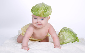 A small baby with a cabbage leaf on his head