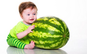A small blue-eyed boy with a big green watermelon
