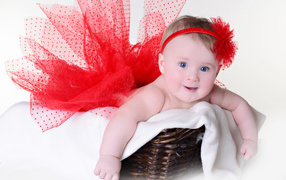 Маленькая голубоглазая девочка в красном красивом платье лежит в корзине