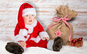 A small child in Santa's suit with a bag