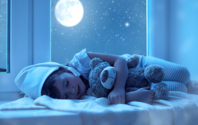 A small child in pajamas sleeps with a soft toy in the background of the moon
