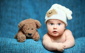 A small child with a beautiful white hat with a teddy bear