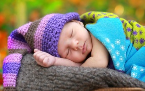 Маленький спящий младенец в вязаной шапке 
