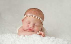 Маленький спящий грудной ребенок с красивым украшением на голове