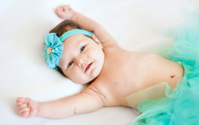 A sweet little baby with a turquoise flower on her head
