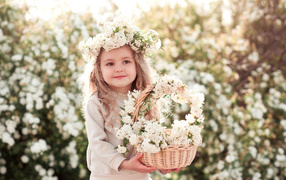 A sweet little girl with a wreath on her head and a basket of white flowers