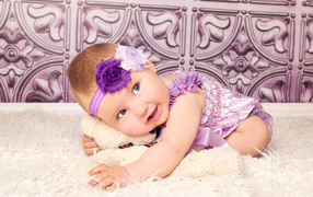 Красивая маленькая девочка в фиолетовом костюме с плюшевым мишкой