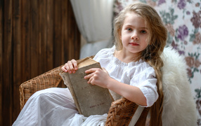 Beautiful little girl in white dress with book