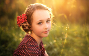 Красивая маленькая девочка с ягодами калины в волосах