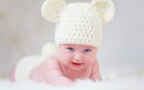 Blue-eyed baby in a white knitted hat with ears