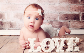 Грудной ребенок с надписью любовь на фоне кирпичной стены