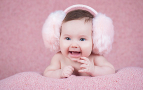 Cute smiling baby in big pink headphones