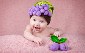 Funny baby in a knitted hat with berries on his head