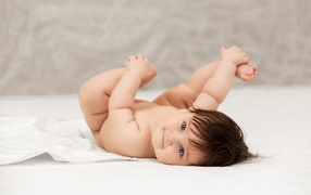 Забавный младенец держится руками за ноги 