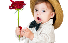 Funny little boy in a hat with a red rose in his hand
