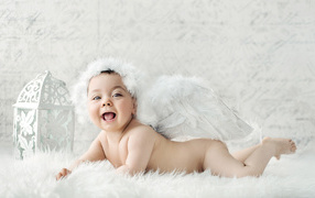 Забавный улыбающийся ребенок с крыльями ангела