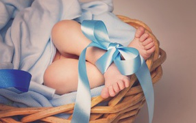 Маленькие ноги младенца с голубым бантом