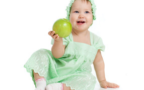 Little blue-eyed girl with a green apple in her hands