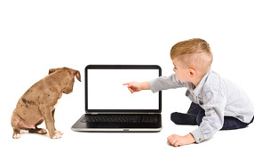 Little boy and a puppy are looking at the laptop screen on a white background