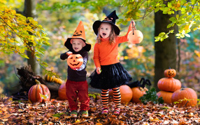 Маленькие мальчик и девочка в костюмах с тыквами на Хэллоуин