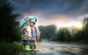 Little boy and girl under an umbrella on the road