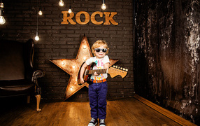 Little boy in fashion glasses with a guitar