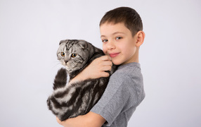 Маленький мальчик с большим котом на сером фоне