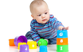 Маленький мальчик с разноцветными игрушками на белом фоне