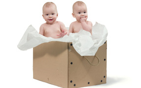 Little children are sitting in a cardboard box with paper