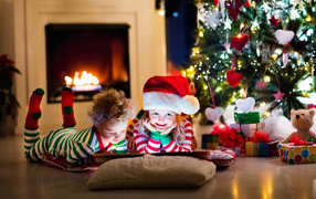 Little children in New Year's costumes under the Christmas tree