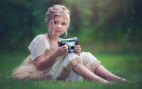 Маленькая русоволосая девочка с фотоаппаратом в руках