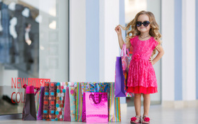 Маленькая модная девочка в красном платье с покупками