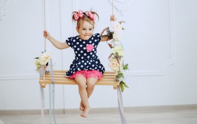 Little funny girl in a pea dress on a swing