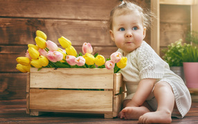 Маленькая забавная девочка с букетом тюльпанов