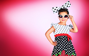 Маленькая девочка в красивом платье в горох на розовом фоне